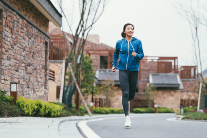 Happy runner in a blue hoodie running down a street